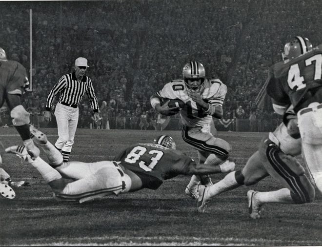 Ohio State quarterback Art Schlichter (10) runs the ball in the 1978 Gator Bowl, a 17-15 loss to Clemson. Tigers defensive tackle Jim Stuckey dives to try to make the tackle. [Dispatch file photo]