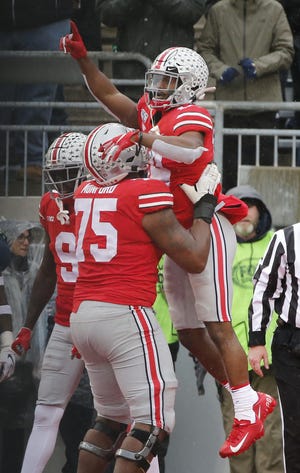 Ohio State offensive lineman Thayer Munford hoists teammate K.J. Hill after the receiver scored a touchdown against Penn State on Nov. 23. [Adam Cairns/Dispatch]