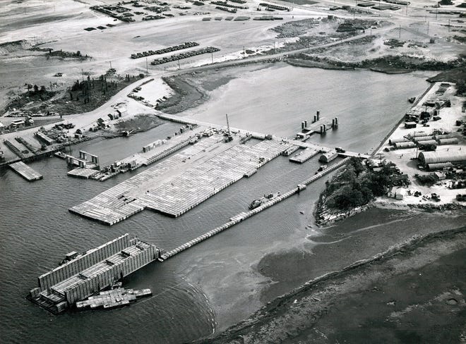 An aerial view of the Advance Base Proving Ground at Davisville on Sept. 29, 1943. Seabees experiment with different pontoon structures, including, to the right, a floating dry dock with stabilizer towers. Quonset huts are to the right. [National Archives]