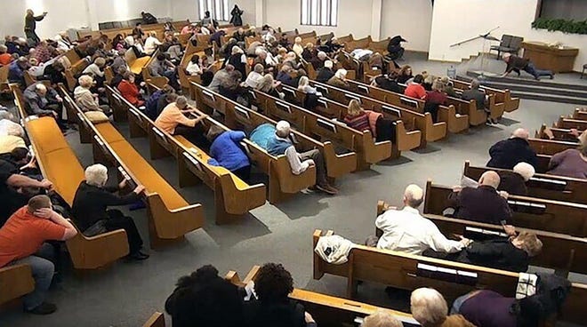 In this still frame from livestreamed video provided by law enforcement, churchgoers take cover while a congregant armed with a handgun, top left, engages a man who opened fire, near top center just right of windows, during a service at West Freeway Church of Christ on Sunday in White Settlement. [West Freeway Church of Christ/Courtesy of Law Enforcement]