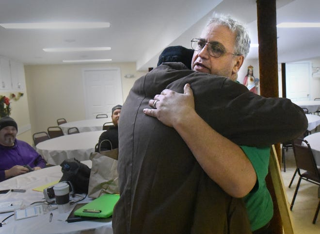 Dave Abbott, right, gets a hug from a person using the warming shelter at St. George Maronite Church in Dover Monday due to the snow storm and cold temperatures. Abbott and others showed up to volunteer and also brought blankets and sleeping bags. [Deb Cram/Fosters.com]