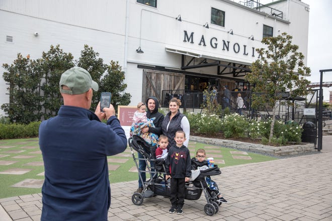 Matthew and Kailey Vieira of Wichita Falls take a photo with their family in front of the Magnolia Market at the Silos in Waco. [Julia Robinson/The Washington Post]