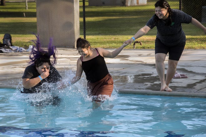 Sianna Mucino, left, and Marlene Rodriguez, both 18, jump into the 47-degree water of Oak Park Pool in Stockton as Marlene's mother, Leticia Rodriguez, hesitates at the first Polar Plunge put on by the city of Stockton and the YMCA of San Joaquin County. [CLIFFORD OTO/THE RECORD]
