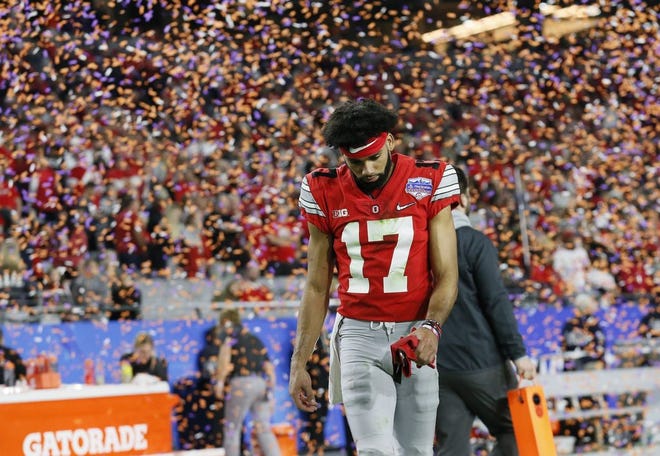 Ohio State Buckeyes wide receiver Chris Olave walks off the field as Clemson-colored confetti falls from the ceiling following the College Football Playoff Semifinal against the Clemson Tigers at the Fiesta Bowl in Glendale, Arizona, on Saturday, Dec. 28. Ohio State lost 29-23.