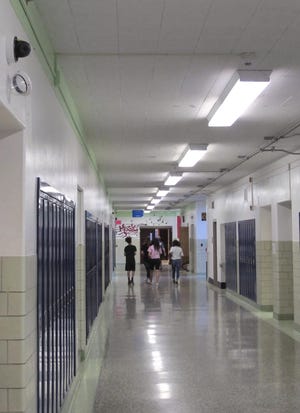 FILE - In this July 10, 2018, file photo, students walk down a hallway at Lockport High School in Lockport, N.Y. On the upper left a camera with facial recognition capabilities hangs on the wall waiting for its installation to be completed. The upstate New York school district has begun using facial recognition technology to look for threats. But civil rights advocates want to stop it, saying it infringes on student privacy. (AP Photo/Carolyn Thompson, File)
