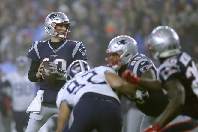 New England Patriots quarterback Tom Brady, left, drops back to pass under pressure from Tennessee Titans defensive end Matt Dickerson in the first half of a wild-card playoff game Saturday in Foxborough, Mass. The Titans led 14-13 in the third quarter at press time. [Charles Krupa/The Associated Press]