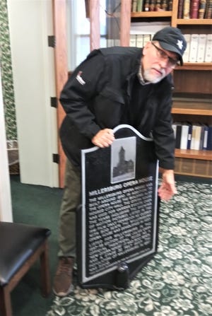 Dan Miller of the Millersburg Lions displays the historic Millersburg Opera House sign to the Holmes County Commissioners. The sign will be displayed outside where the building once stood in downtown. Miller proposed the commissioners obtain similar signs for the courthouse and old jail, two other historic Millersburg buildings.