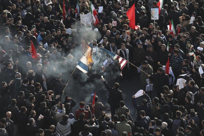 Mourners burn mock flags of the U.S. and Israel during a funeral ceremony for Iranian Gen. Qassem Soleimani and his comrades, who were killed in Iraq in a U.S. drone strike on Friday, at the Enqelab-e-Eslami (Islamic Revolution) square in Tehran, Iran, Monday, Jan. 6, 2020. (AP Photo/Ebrahim Noroozi)