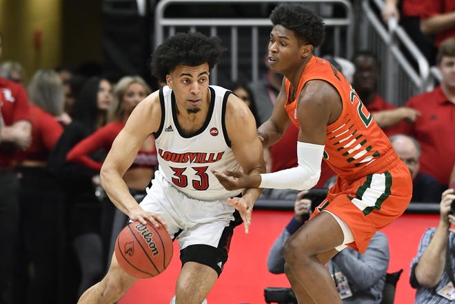 Louisville forward Jordan Nwora (33) drives around Miami guard Kameron McGusty during the first half Tuesday in Louisville, Ky. [Timothy D. Easley/The Associated Press]
