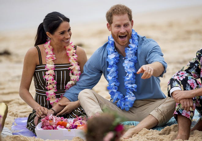 In this Oct. 19, 2018, file photo Britain's Prince Harry and Meghan, Duchess of Sussex, meet with a local surfing community group, known as OneWave, raising awareness for mental health and wellbeing in a fun and engaging way at Bondi Beach in Sydney, Australia. In a stunning declaration, Prince Harry and his wife, Meghan, said they are planning "to step back" as senior members of the royal family and "work to become financially independent." A statement issued by the couple Wednesday also said they intend to "balance" their time between the U.K. and North America. [DOMINIC LIPINSKI/POOL VIA ASSOCIATED PRESS]