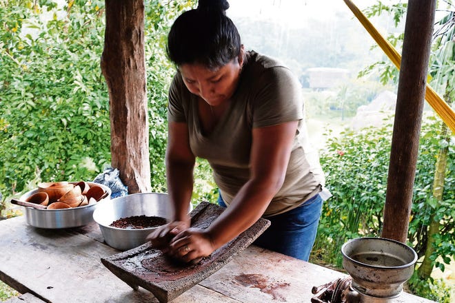 A worker turns processed cacao into a paste. [Rachel Forrest]