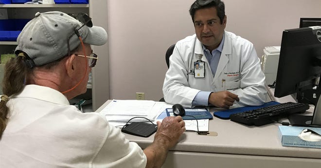Charlie Parks talks about the water-borne Mycobacterium marinum infection in his right hand with Dr. Zubin Pathaki at the Veterans Affairs Medical Center in West Palm Beach on May 11, 2018. (Photo: TYLER TREADWAY/TCPALM)