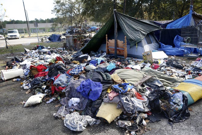 Clothes and other belongings are scattered outside a tent at Dignity Village, a homeless encampment near Grace Marketplace in northeast Gainesville on Tuesday. Residents have been told that the area will be closed in March. [Brad McClenny/Staff photographer]
