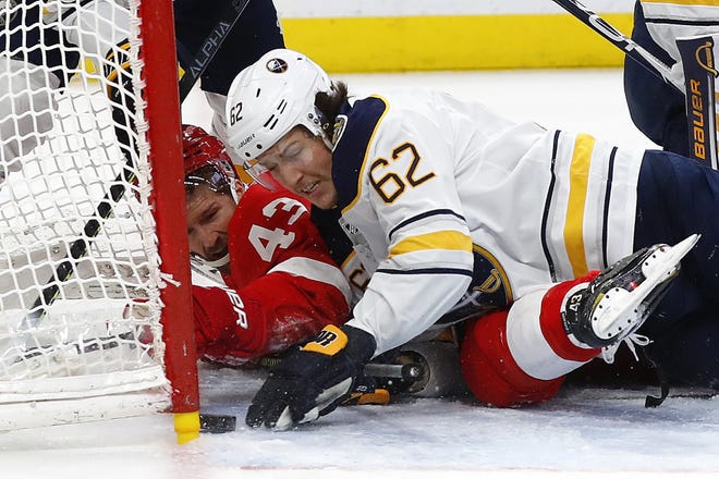 Buffalo Sabres defenseman Brandon Montour (62) pushes the puck from the goal as Detroit Red Wings left wing Darren Helm (43) looks on in the second period of an NHL hockey game Sunday, Jan. 12, 2020, in Detroit. (AP Photo/Paul Sancya)