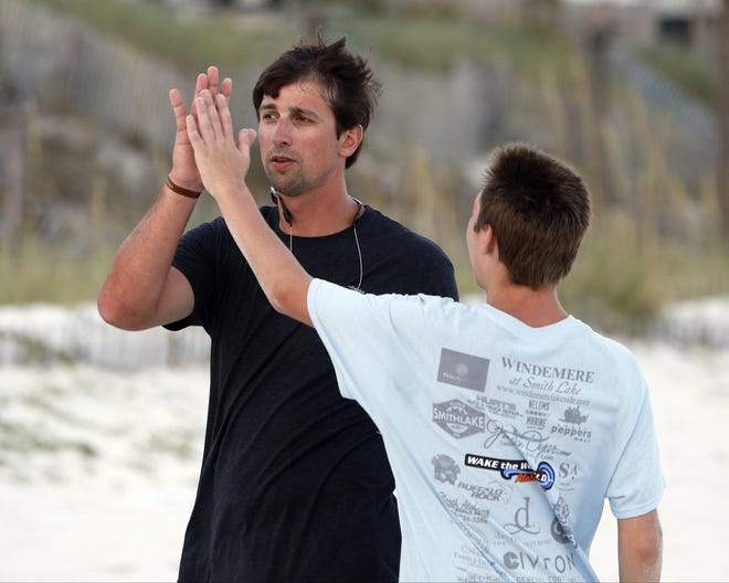 Brodie Croyle gets a high five from Caleb on Tuesday Aug. 5, 2014 while playing football at Panama City Beach, Florida. More than 200 family members from the Big Oak Ranch spent a week at the Laguna Beach Christian Retreat in Panama City Beach during their annual family trip. [Staff file photo]