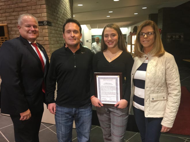 Caitlin Groves (holding letter of recognition), an eighth-grader at Cecelia Snyder Middle School in Bensalem, was honored at the Bensalem Council meeting Monday by the Bensalem Police Department for saving another student who was suicidal. With her are, from left. Director of Public Safety Frederick Harran; Caitlin’s father, James Groves; and her mother, Nicole Groves. [PEG QUANN / STAFF PHOTOJOURNALIST]