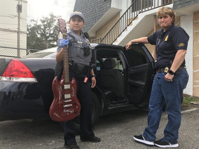 Daytona Beach police officers display one of the valuable autographed guitars stolen from a storage unit, recovered from OK Pawn, Tuesday, Jan. 14,2020. [News-Journal / Frank Fernandez]