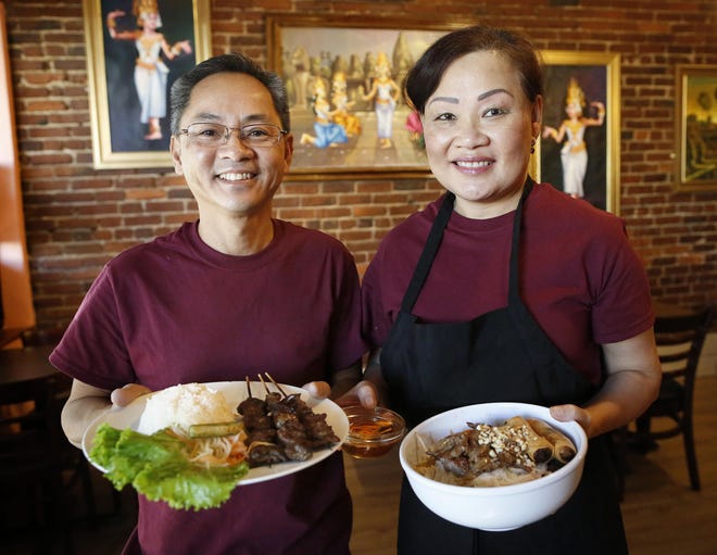 Bo and Leanna Prum, who are from Cambodia, hold two of their signature dishes at their new restaurant, Prum's Kitchen, downtown on Main Street in Gainesville on last Wednesday. [Brad McClenny/Staff photographer]