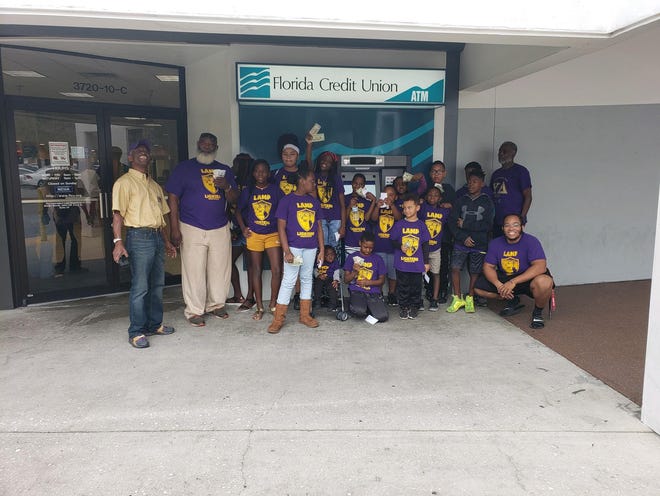 Members of the Lamplighters’ mentoring program visited Florida Credit Union to deposit $25 in their bank accounts. The money was a reward from their academic success in school. The program members were accompanied by members of the Beta Pi chapter of Omega Psi Phi Fraternity Inc., which sponsors the program. [SUBMITTED PHOTO]