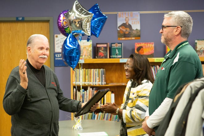 Jim Brewer, founder of Warm Little Ones Coat Fund, reacts after recieving an appreciation award from Tiffany Anderson, Topeka Public Schools superintendent, and Fred Willer, a social worker at Highland Park High, on Wednesday at Ross Elementary School. [Evert Nelson/The Capital-Journal]