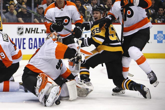 The Penguins' Jake Guentzel (59) celebrates scoring on the Flyers’ goaltender Brian Elliott during an October game, [GENE J. PUSKAR / ASSOCIATED PRESS FILE] (