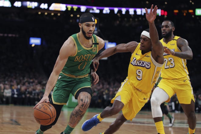 Celtics forward Jayson Tatum drives to the basket against Lakers guard Rajon Rondo and forward LeBron James during the first half of Monday's game in Boston. [Charles Krupa/The Associated Press]