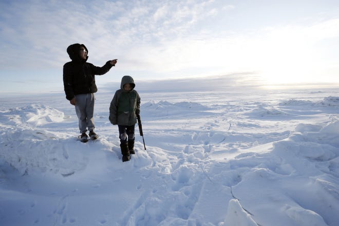 In this Saturday, Jan. 18, 2020, photo, George Chakuchin, left, and Mick Chakuchin look out over the Bering Sea near Toksook Bay, Alaska. The first Americans to be counted in the 2020 Census starting Tuesday, Jan. 21, live in this Bering Sea coastal village. The Census traditionally begins earlier in Alaska than the rest of the nation because frozen ground allows easier access for Census workers, and rural Alaska will scatter with the spring thaw to traditional hunting and fishing grounds. [GREGORY BULL/AP]