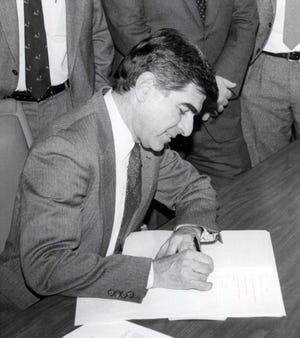During a Jan 1990 visit to town, Gov. Michael Dukakis signs the Cape Cod Commission Bill into law at the First District Court House in Barnstable. [BARNSTABLE PATRIOT FILES/W.B. NICKERSON CAPE COD HISTORY ARCHIVES]