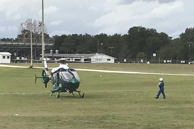 At Booster Stadium in Ocala, a crew member carries an injured 2-year-old girl to a FlightCare helicopter for transport to UF Health Shands Hospital in Gainesville. [Austin L. Miller/Star-Banner]