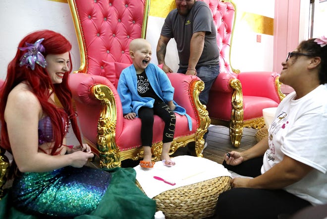 Trinity Gyetvai, 4, who has stage 4 neuroblastoma, laughs as she jokingly pulls her foot away from Chelsee Florence, right, who is giving her a pedicure. Caitlin Seney, dressed as Trinity's favorite Disney princess, Ariel, joined her for a Princess Spa Day for Trinity at Trinity Day Spa in Gainesville Saturday. [Brad McClenny/Staff photographer]