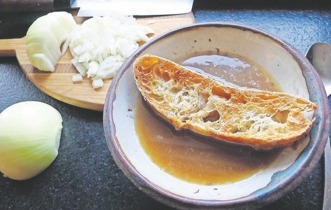 A crusted bowl of French onion soup, with minced onions in the background. [ARI LEVAUX]