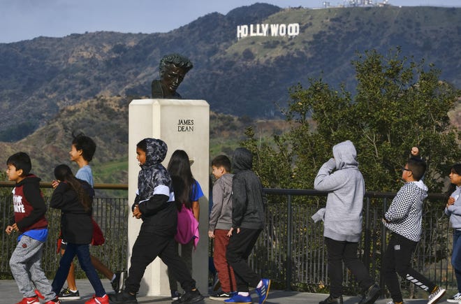 School children walk past a bust of actor James Dean during a field trip, at the Griffith Observatory in the Griffith Park area of Los Angeles. Travis Cloyd, who is leading the revival of Dean for his appearance in "Finding Jack," says his company will eventually offer the late actor's digital likeness for a range of roles in movies, TV and video games. [RICHARD VOGEL/ASSOCIATED PRESS]