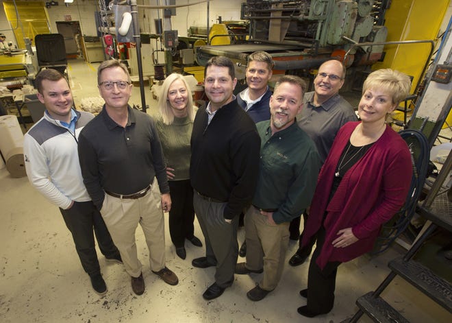 Hubco employees Ben Lippold, left, Fred Moore, Phyllis Keffer, company president Trey McPherson, David Patterson, back, Chris DeMeyer, Lyle Smart, back, and Shari Stewart stand by one of the oldest machines at Hubco, which has been chosen as the Hutchinson / Reno County Chamber of Commerce Small Business of the Month for January. [Sandra J. Milburn/HutchNews]