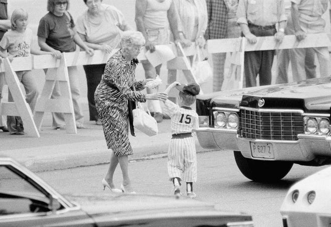 Four-year-old Michael Munson, wearing a smaller version of his father's New York Yankees uniform, leaves the funeral services for Yankees catcher Thurman Munson at Memorial Civic Center, Aug. 6, 1979. Michael was taken from the services after they began by an unidentified family friend, left. (AP Photo/Brian Horton)