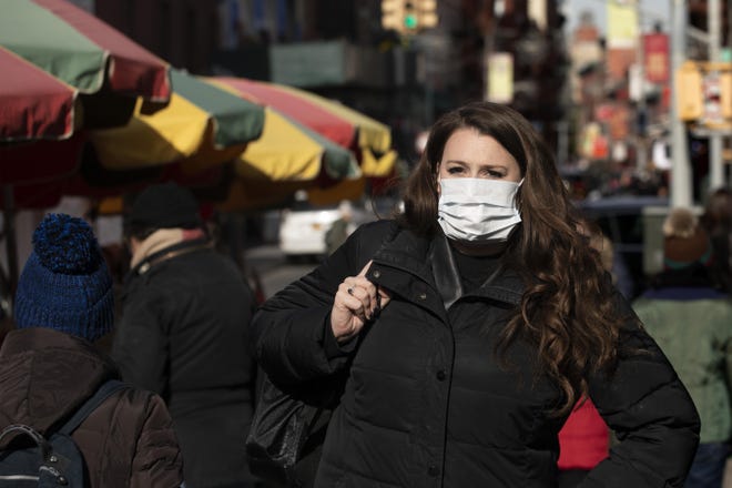 A woman, who declined to give her name, wears a mask, Thursday in New York. She works for a pharmaceutical company and said she wears the mask out of concern for the coronavirus. "I'd wear a mask if I were you," she said. For the first time in the U.S., the new virus from China has spread from one person to another, health officials said Thursday. [AP Photo/Mark Lennihan]