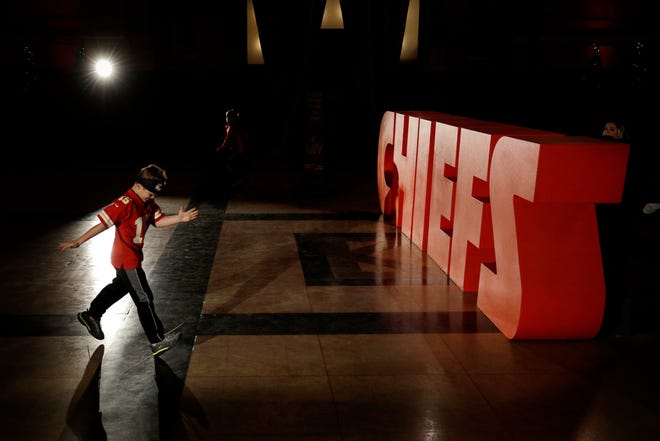 A boy in a Kansas City Chiefs jersey approaches a Chiefs logo at Union Station in Kansas City. [Charlie Riedel/The Associated Press]