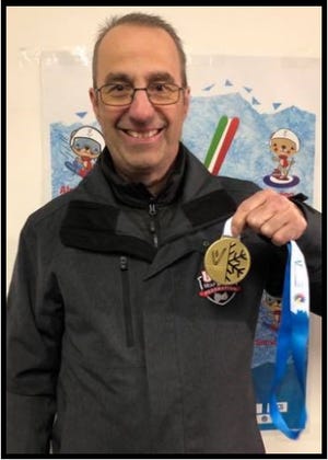 David Zimmerman is seen holding up one of his national hockey team’s gold medals.