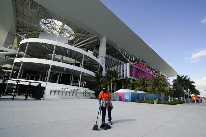 A worker sweeps outside of Hard Rock Stadium, Tuesday, Jan. 28, 2020, in Miami Gardens, Fla., in preparation for the NFL Super Bowl 54 football game between the San Francisco 49ers and the Kansas City Chiefs. (AP Photo/Chris Carlson)