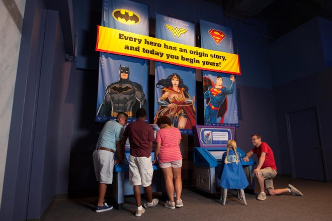 Visitors examine one of the exhibits in “DC Superheroes: Discover Your Superpowers,” opening Saturday at COSI Columbus. [Jennifer Dummett]