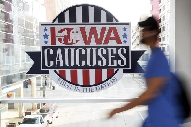 A pedestrian walks past a sign for the Iowa Caucuses on a downtown skywalk Tuesday in Des Moines, Iowa. [CHARLIE NEIBERGALL/ASSOCIATED PRESS]