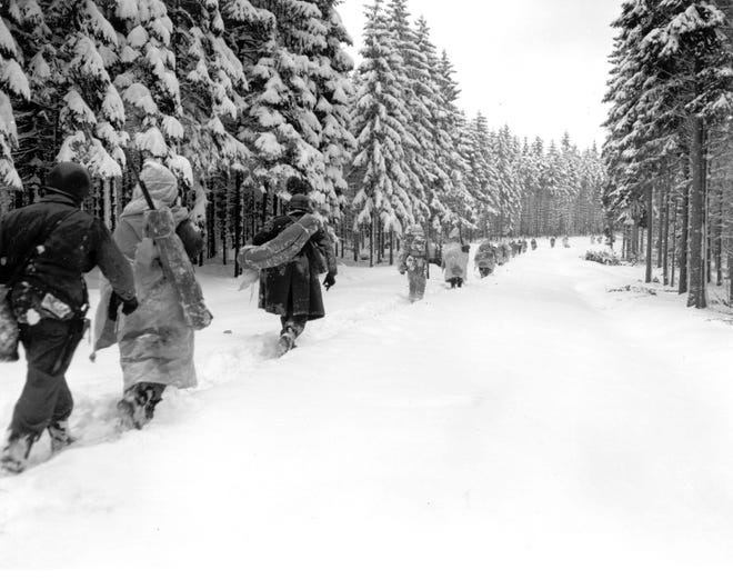 In this Jan. 28, 1945 file photo, U.S. troops of the 82nd Airborne division travel on a snow-covered fire track in the woods as they move forward in the Ardennes region in Belgium during the Battle of the Bulge. [ ARMY SIGNAL CORP ]