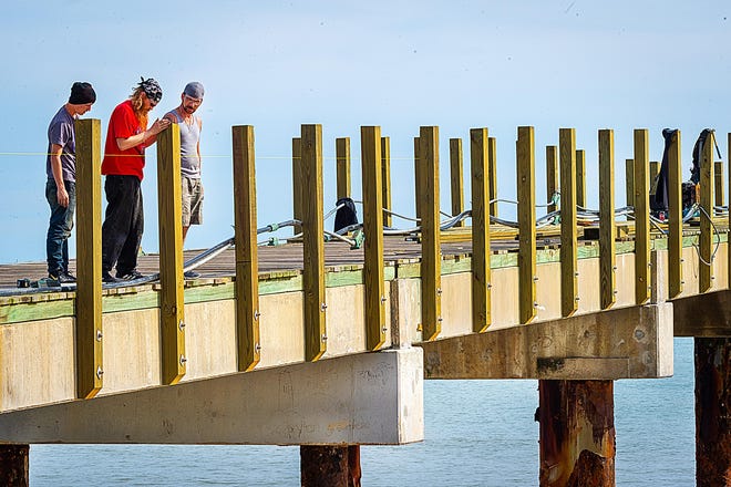 Men work to install new guard rails post on the side of the St. Johns County Ocean and Fishing Pier in St. Augustine Beach on Tuesday. [PETER WILLOTT/THE RECORD]