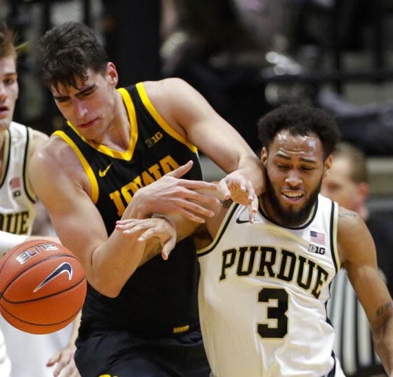 Iowa center Luka Garza (55) fights for the ball against Purdue guard Jahaad Proctor (3) Wednesday during the game in West Lafayette, Indiana. Michael Conroy/The Associated Press]