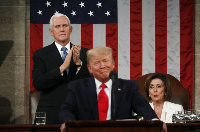 Vice President Mike Pence stands and applauds as Speaker of the House Nancy Pelosi reacts to President Donald Trump as he delivers his State of the Union address to a joint session of Congress Tuesday night.[Reuters News pool photo/Leah Millis]