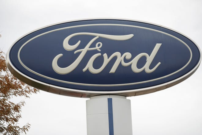 FILE - In this Oct. 20, 2019, file photo, the company logo stands over a long row of unsold vehicles at a Ford dealership in Littleton, Colo. Ford Motor Co.'s profit in 2019 plunged by more than $3.6 billion, weighed down by slowing U.S. sales, the cost of a botched SUV launch and some big pension expenses. (AP Photo/David Zalubowski, File)