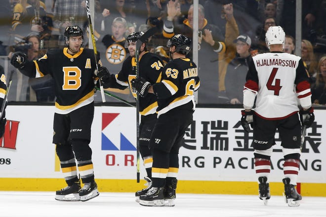 Bruins center Patrice Bergeron (left) celebrates his goal with teammates Brad Marchand (middle right) and Jake DeBrusk as Coyotes defenseman Niklas Hjalmarsson (far right) skates away during the second period of Boston's 4-2 win over Arizona on Saturday. [AP Photo/Winslow Townson]