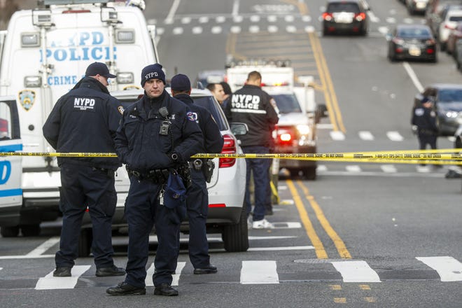 New York City police officers work the scene of a police involved shooting outside the 41st precinct Sunday in New York. [John Minchillo/The Associated Press]