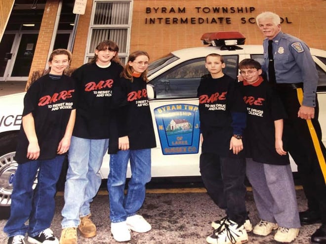 Joseph “Todd” Duffy, right, best known to students as Officer Duffy, is pictured in front of Byram Intermediate School in an undated photo with students in the DARE, or Drug Abuse Resistance Education, program. He served as the Byram Township Police Department’s DARE officer beginning in 1989. [Submitted photo]