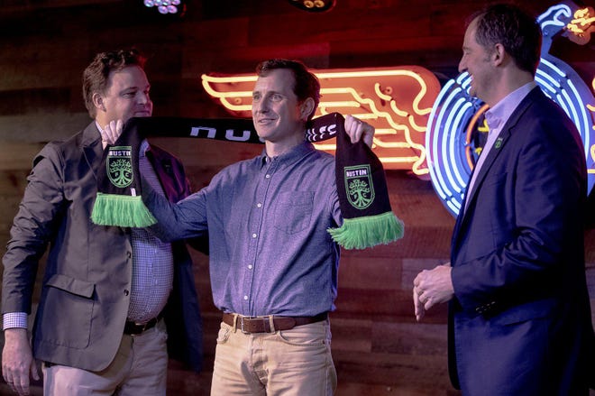 Austin FC majority owner Anthony Precourt, left, and Austin FC president Andy Loughnane, right, present Yeti co-founder Roy Seiders an Austin FC scarf at Yeti's flagship store on Monday. Yeti and Austin FC announced a multi-year jersey sponsorship. [NICK WAGNER/AMERICAN-STATESMAN]
