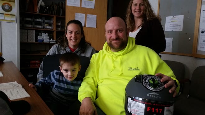James Thomas holds the helmet he received from Motorcycle Ohio on Friday. Shown with him are son Jaxson, 3, wife Karla Thomas (at left) and Michele Piko, statewide coordinator for motorcycle Ohio. (TimesReporter.com / Nancy Molnar)
